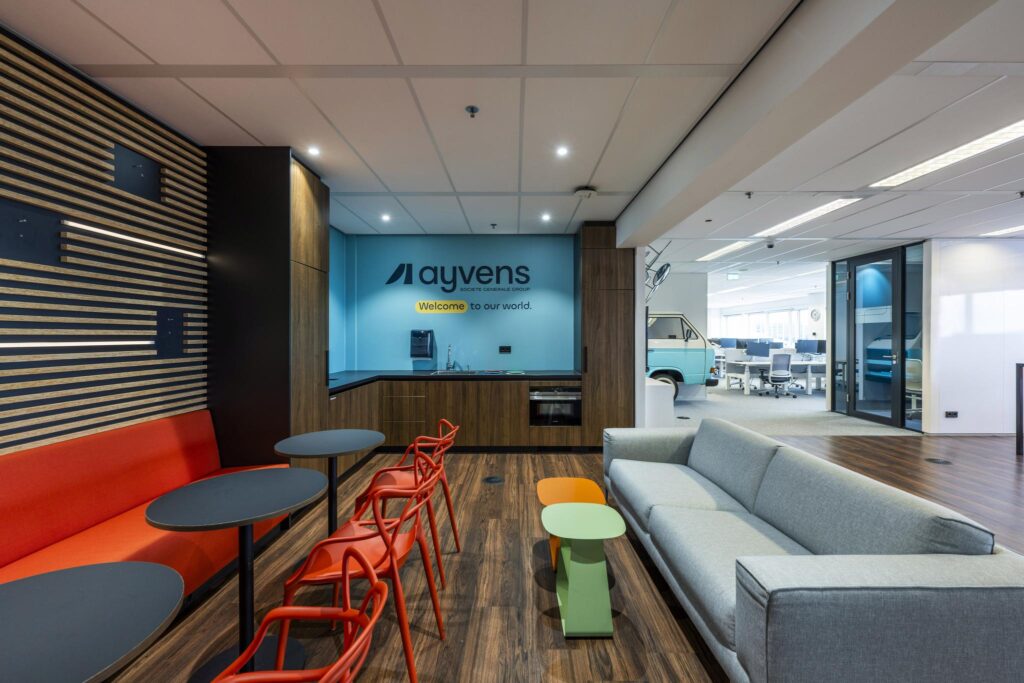 Moderne kantoorruimte van Ayvens aan de Johan Huizingalaan met kleurrijk zitgedeelte en open werkplekken op de achtergrond.